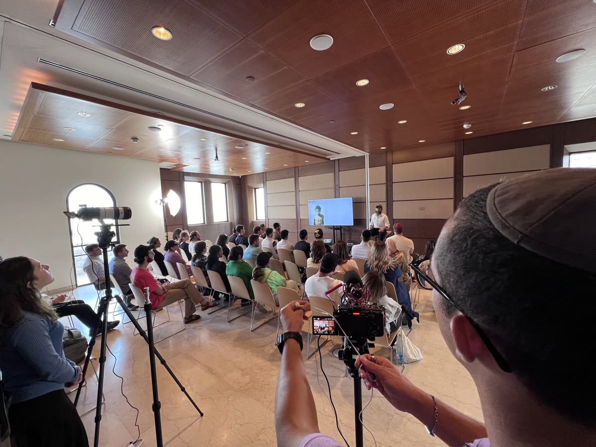 Filming a class in a hall, the audience seated
